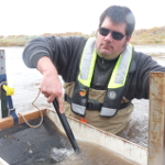 Tim Grabowski clears the screen of a Moore egg collector in the Rio Grande in Albuquerque, New Mexico